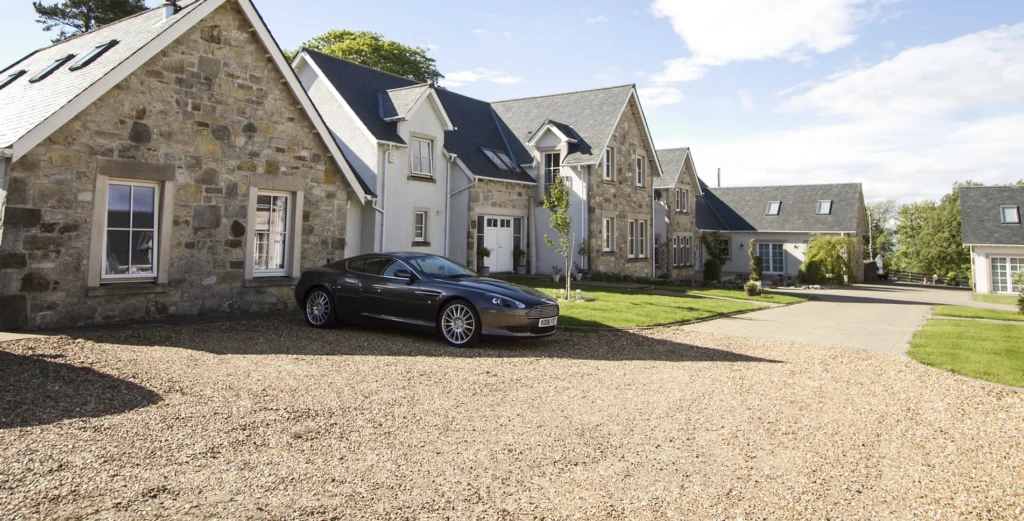 Stone-built luxury homes with a car parked on a gravel driveway, by The Good House Company