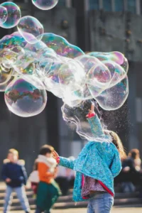 An image of a child running through large bubbles